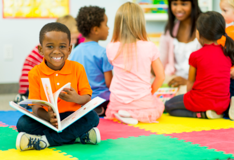 Untitled design29 | ransom district library A child reading a book and smiling at the camera