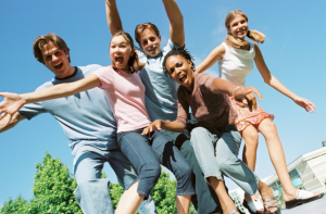 A stock image of a group of teens looking down and smiling at a camera