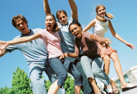 A stock image of a group of teens looking down and smiling at a camera.