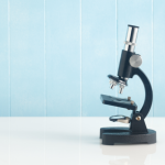A microscope against a light blue backdrop.