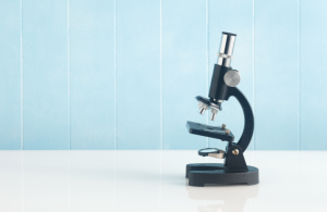 A microscope against a light blue backdrop