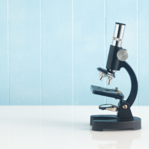 A microscope against a light blue backdrop.