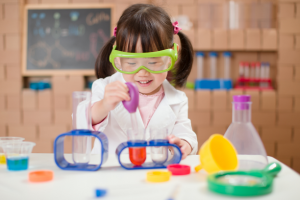 Little girl with safety goggles and a lab coat conducting science experiments