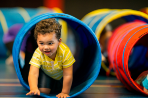 A young child crawling through a play tunnel