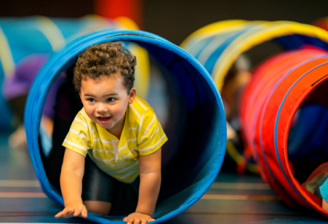 A young child crawling through a play tunnel