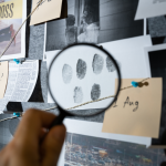 Person using a magnifying glass to look at fingerprints.