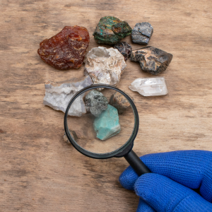 A person using a magnifying glass to look at rocks.