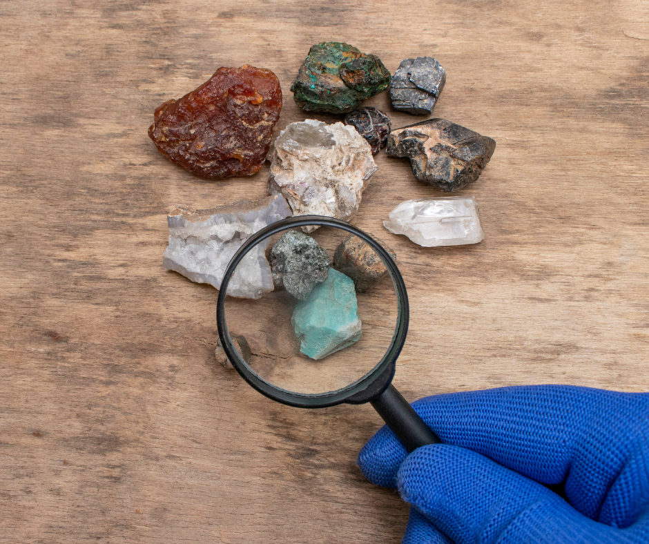 A person using a magnifying glass to look at rocks.