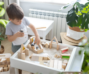 A little boy playing with blocks and a sand table