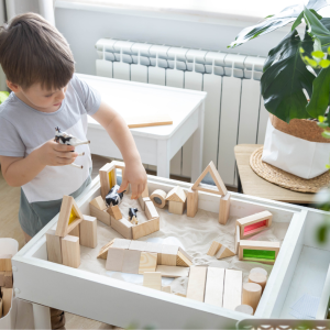 A little boy playing with blocks and a sand table.