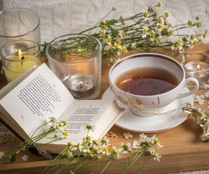 A tray with a cup of tea flowers and an open book