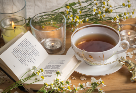 A tray with a cup of tea flowers and an open book