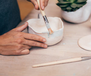 An up close image of a person painting a ceramic pot