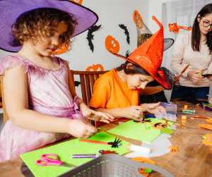 Two children and their mom making halloween crafts at a table